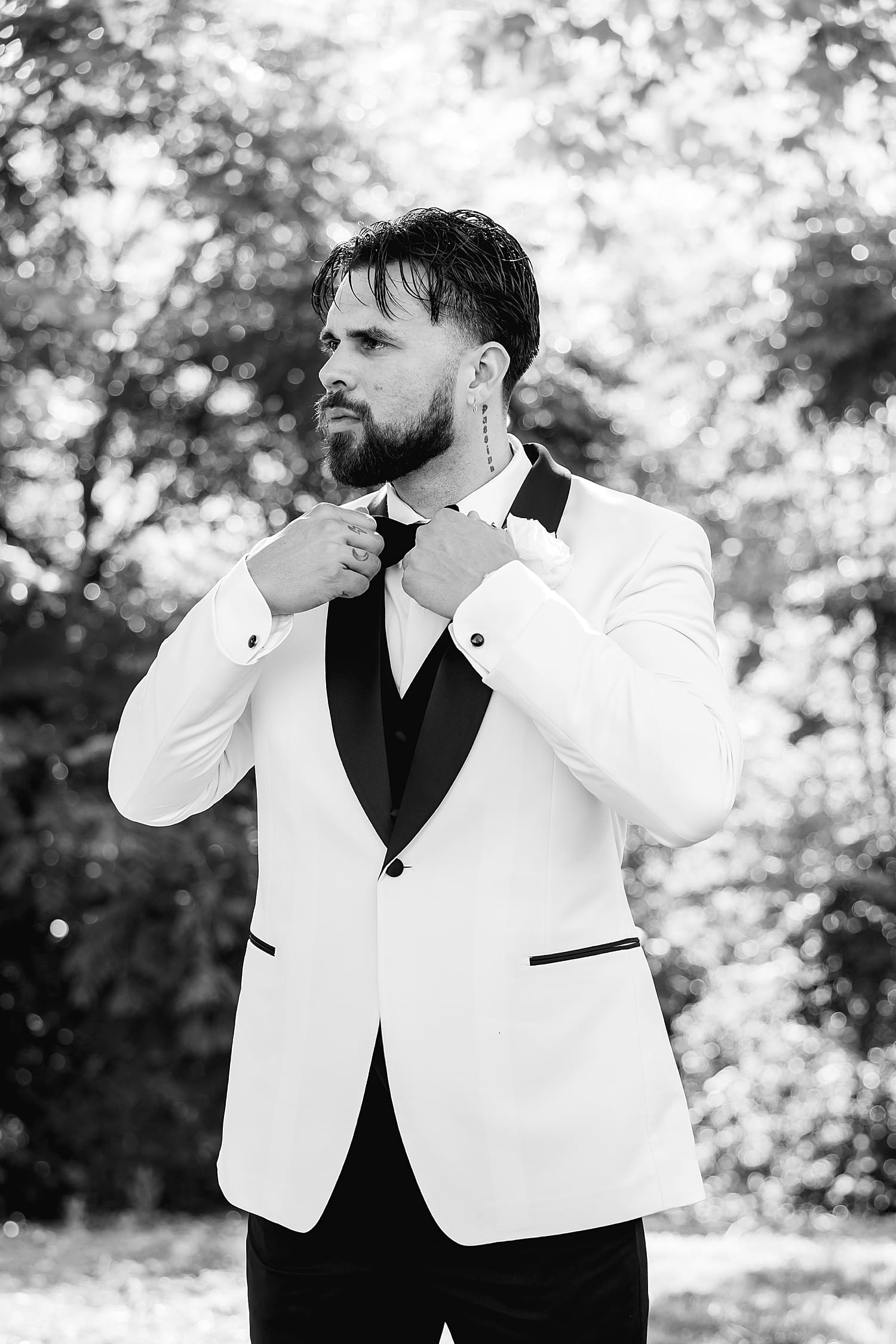 man in white and black tux adjusts collar by Southern California photographer
