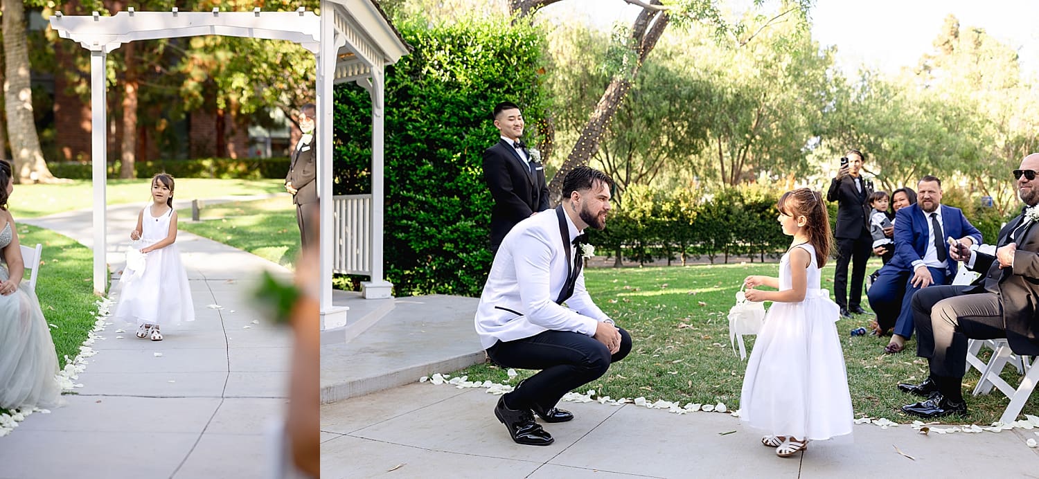 groom kneels as flower girl approaches during Summer wedding in Irvine