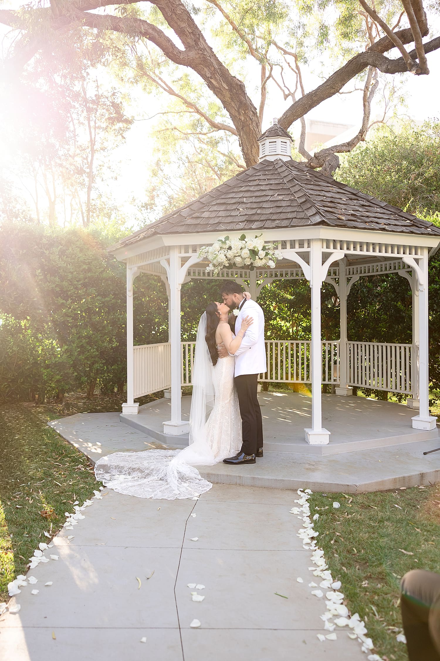 newlyewds share a kiss under golden hour by gazebo for Summer wedding in Irvine