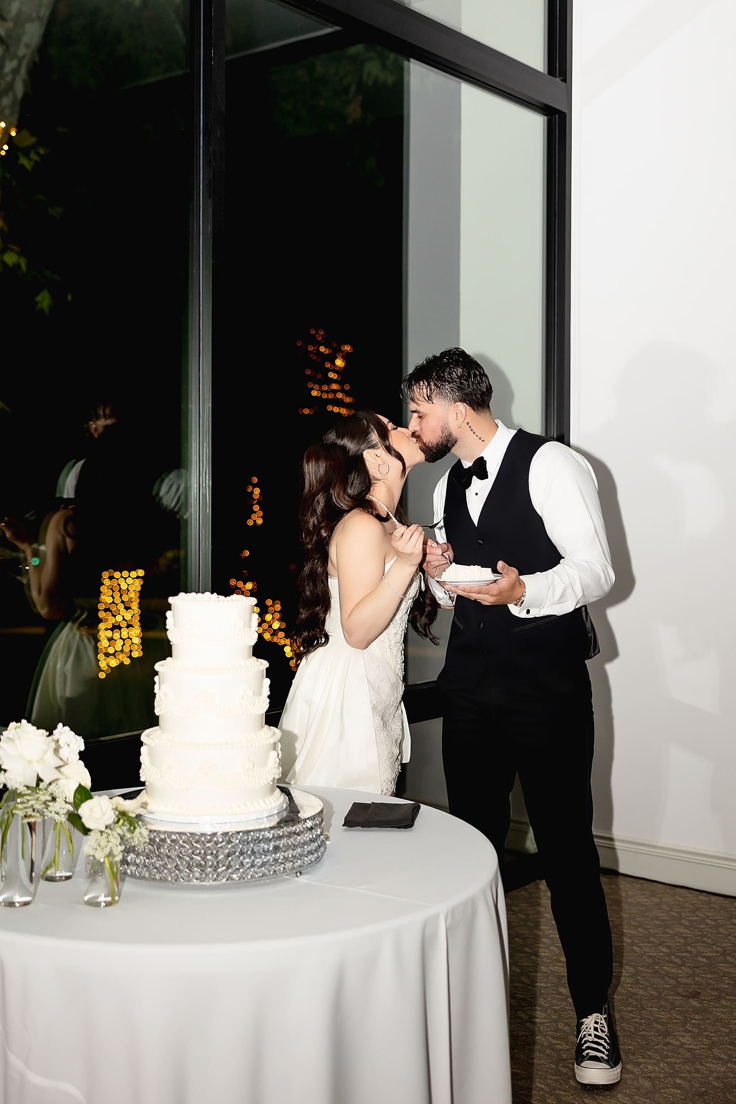newlyweds share a kiss after cutting white cake for Summer wedding in Irvine