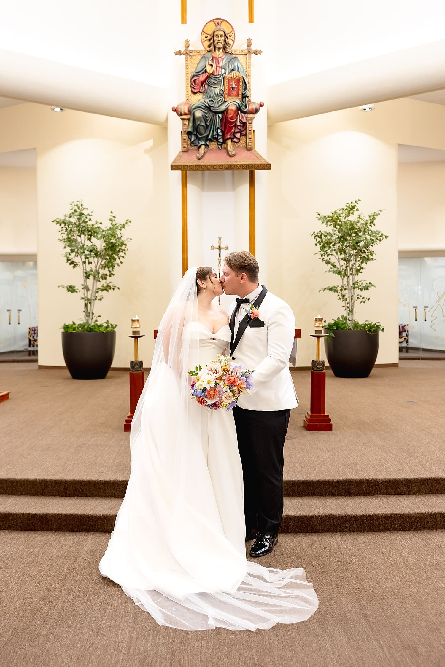 newlyweds share a kiss at catholic alter before reception at University Club by Wedgewood Weddings
