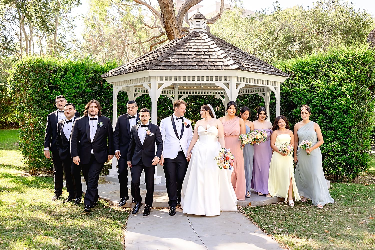 newlyweds and their bridal party walking away from gazebo by Southern California wedding photographer