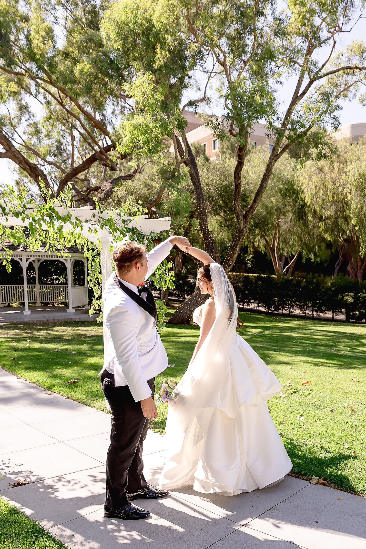 man spins his bride on sidewalk in garden by Desiree Ashley Photography