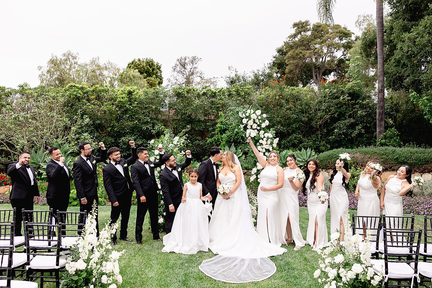newlyweds stand on lawn with their wedding party documenting their full love story