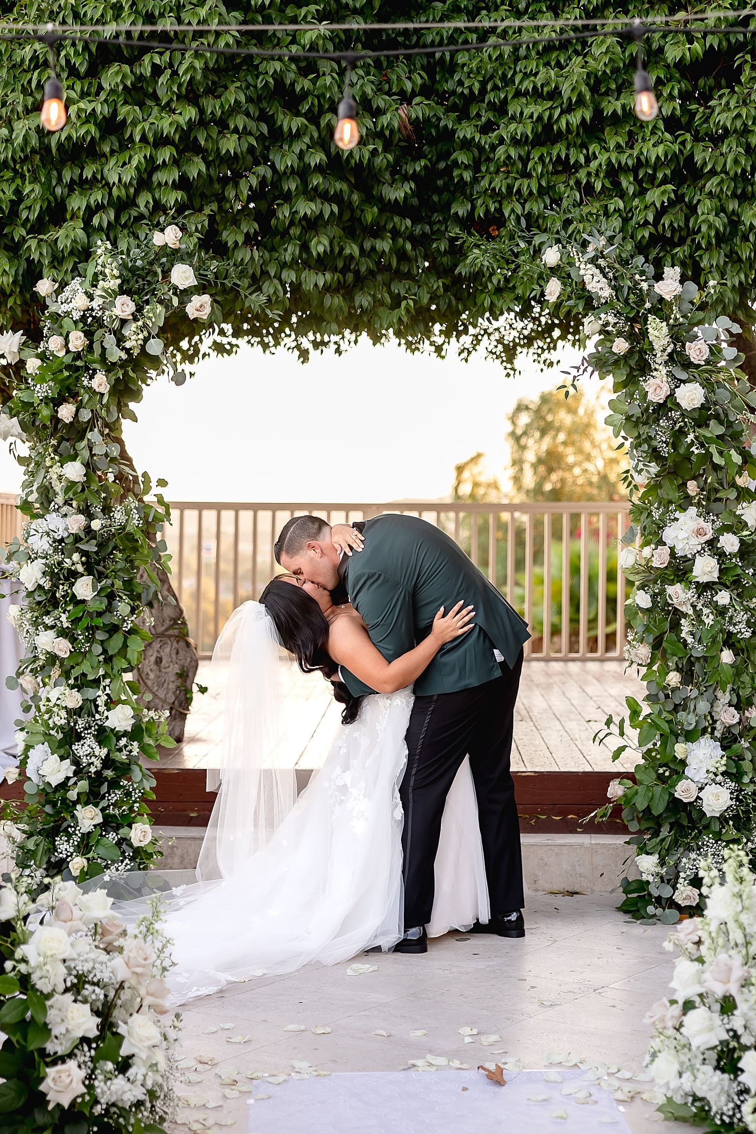 newlyweds share a dip kiss at floral alter by Southern California wedding photographer