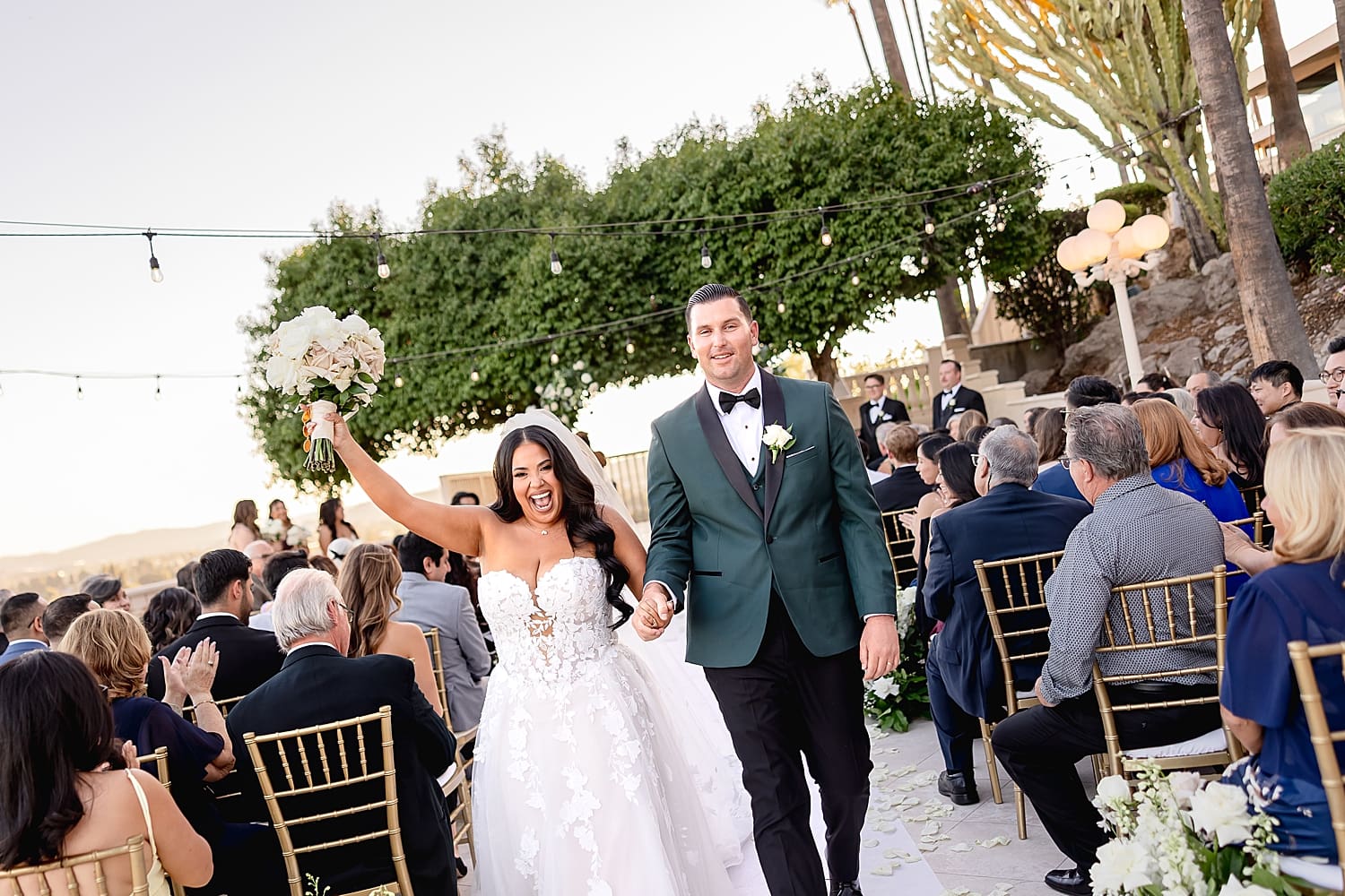 husband and wife throw hands up in the air after ceremony in celebration by Desiree Ashley Photography