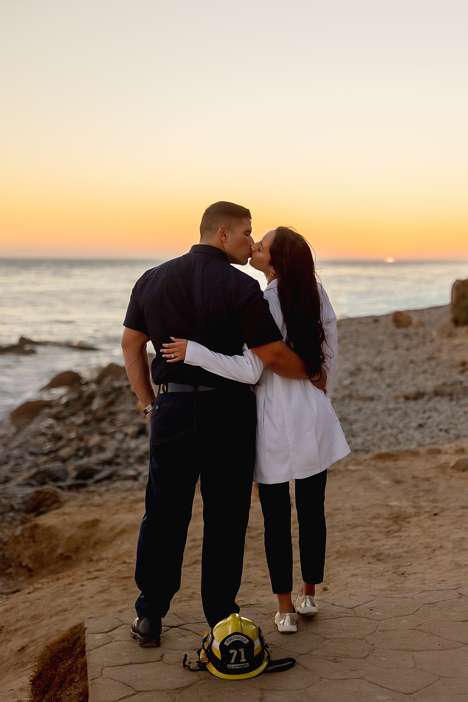 couple in their uniforms kiss during sunset at the beach for unique couples session idea