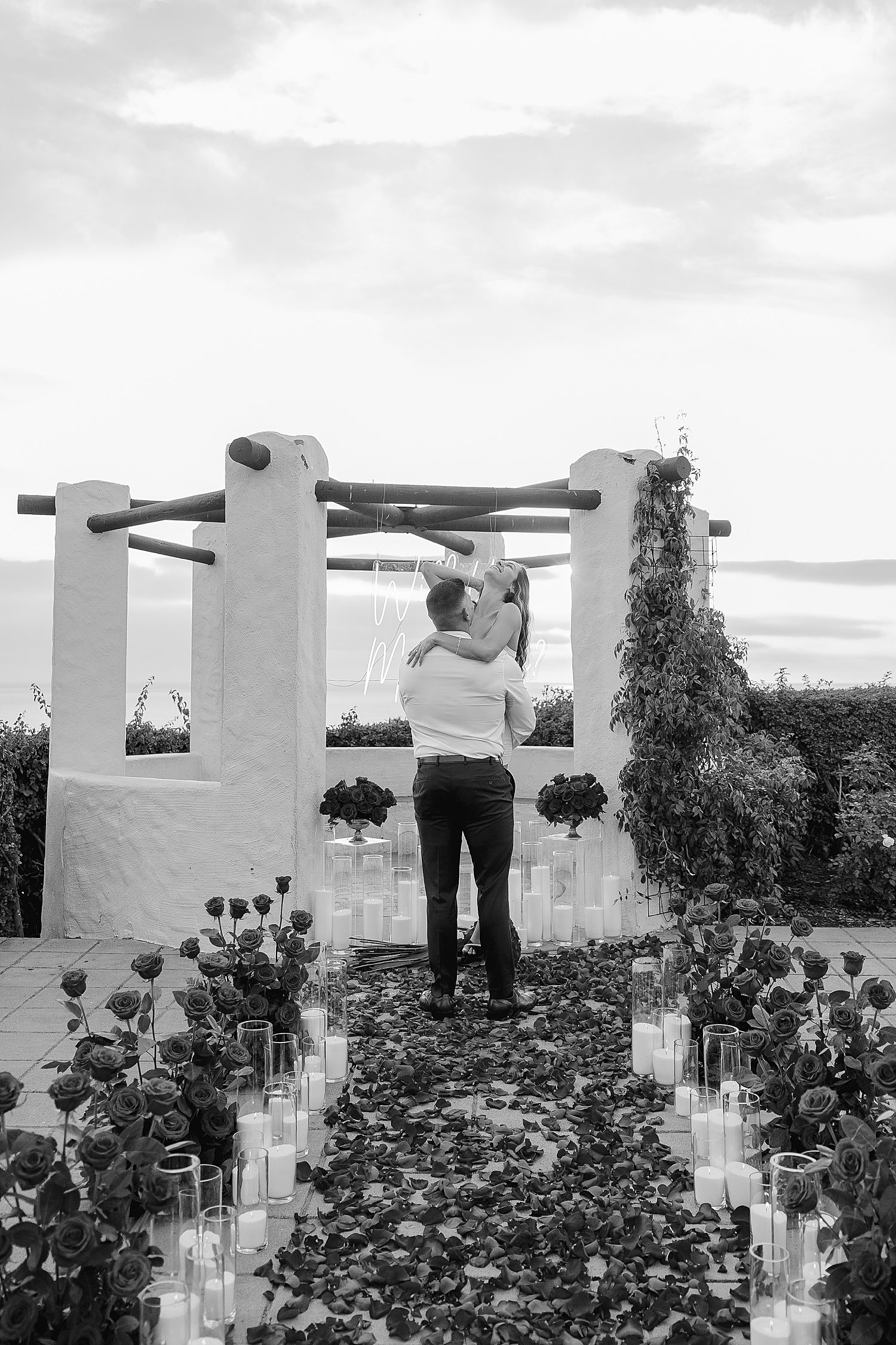 man lifts up his new bride-to-be as she laughs by Southern California wedding photographer