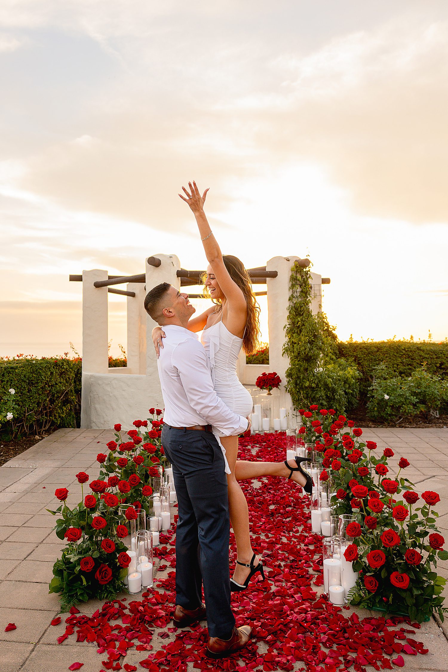 brunette raises her hand in the air showing off new diamond ring by Desiree Ashley Photography