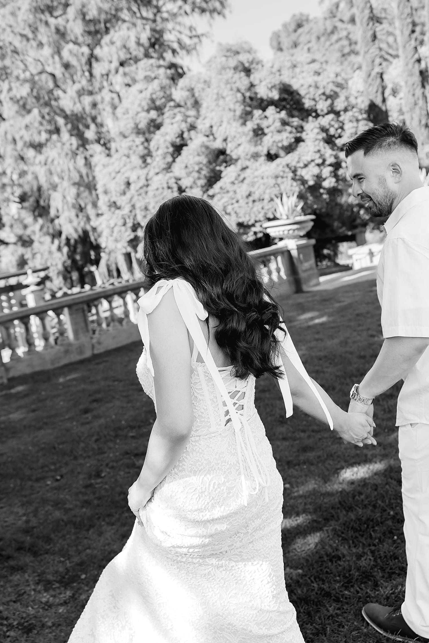 couple walks hand in hand through lush garden by Southern California wedding photographer