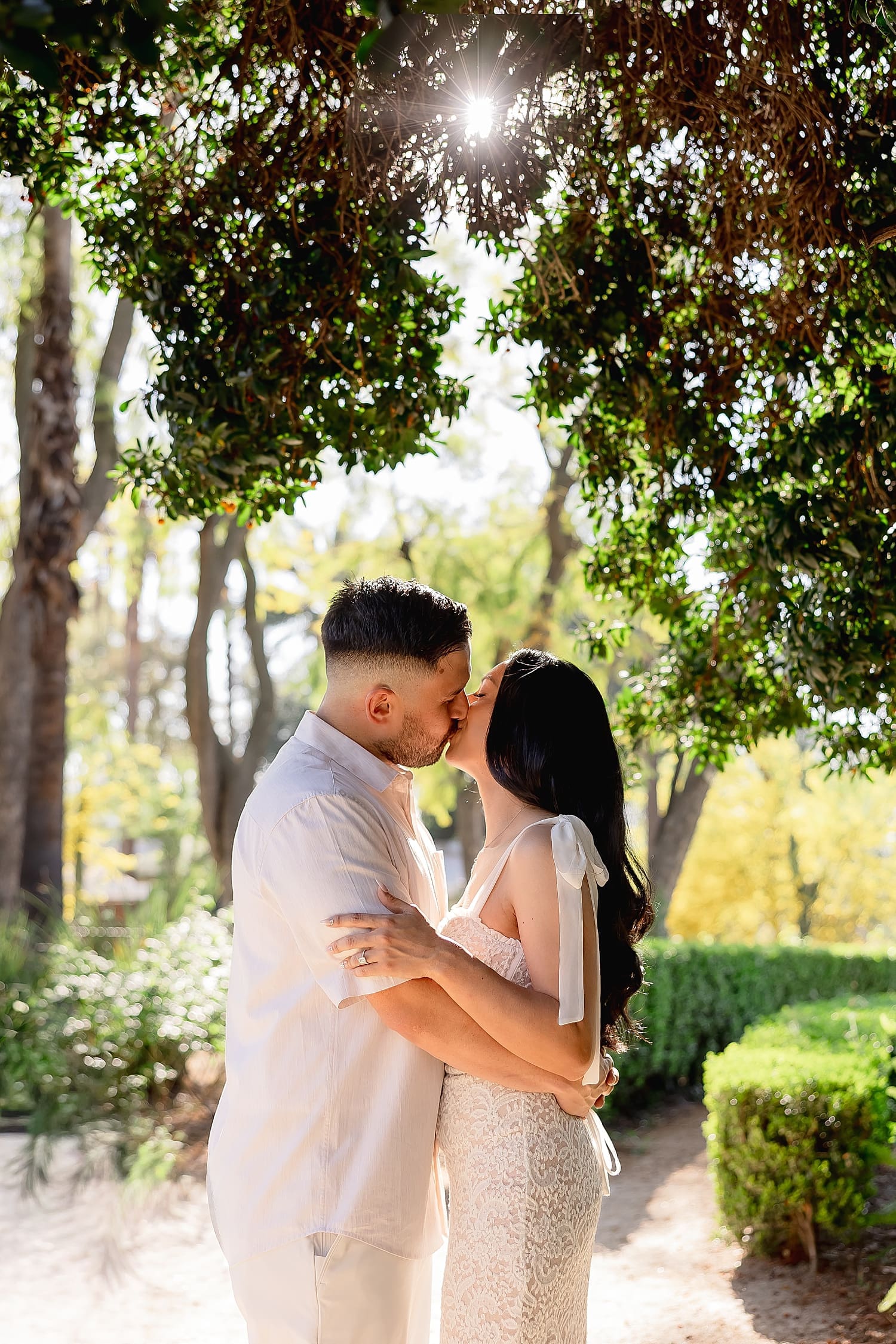 man and woman share a kiss under big tree during golden hour by Desiree Ashley Photography