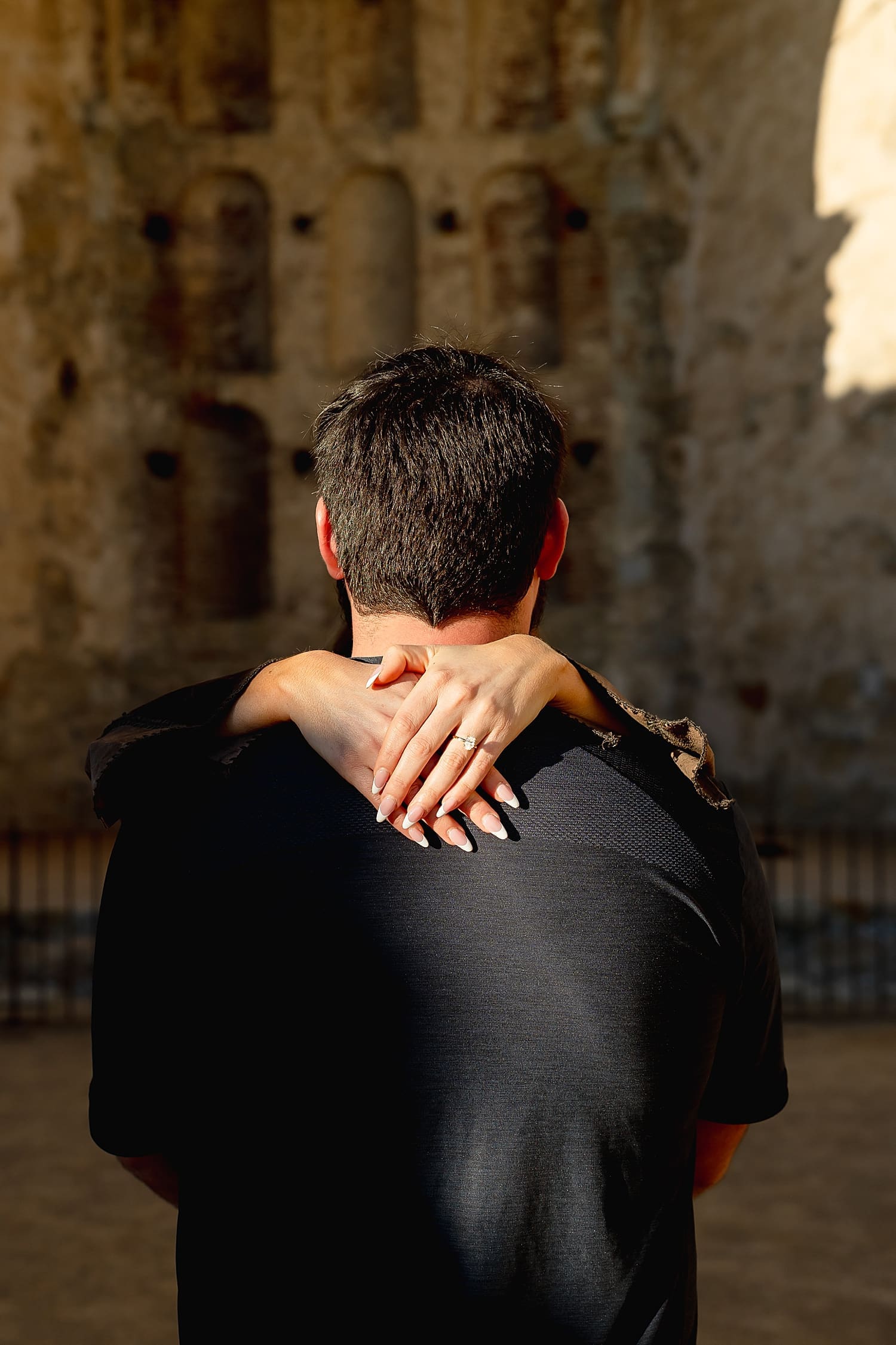 woman wraps her arms around her fiance, showing off diamond ring by Southern California wedding photographer