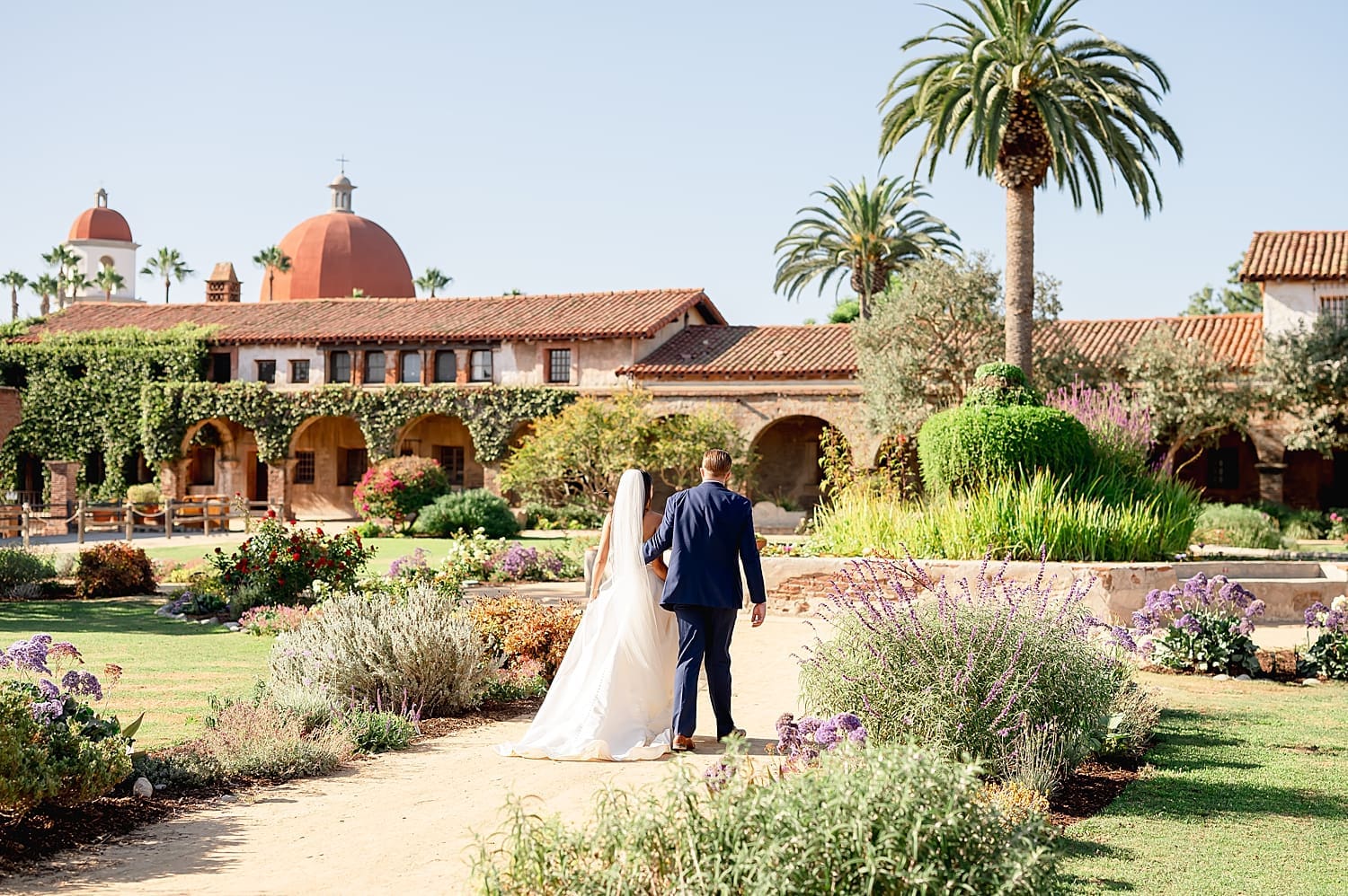 couple walk on winding pathway in beautiful garden by Southern California wedding photographer