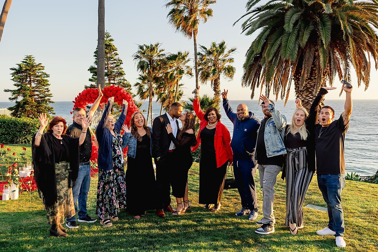 family raises their hands in cheers after couple gets engaged by Desiree Ashley Photography
