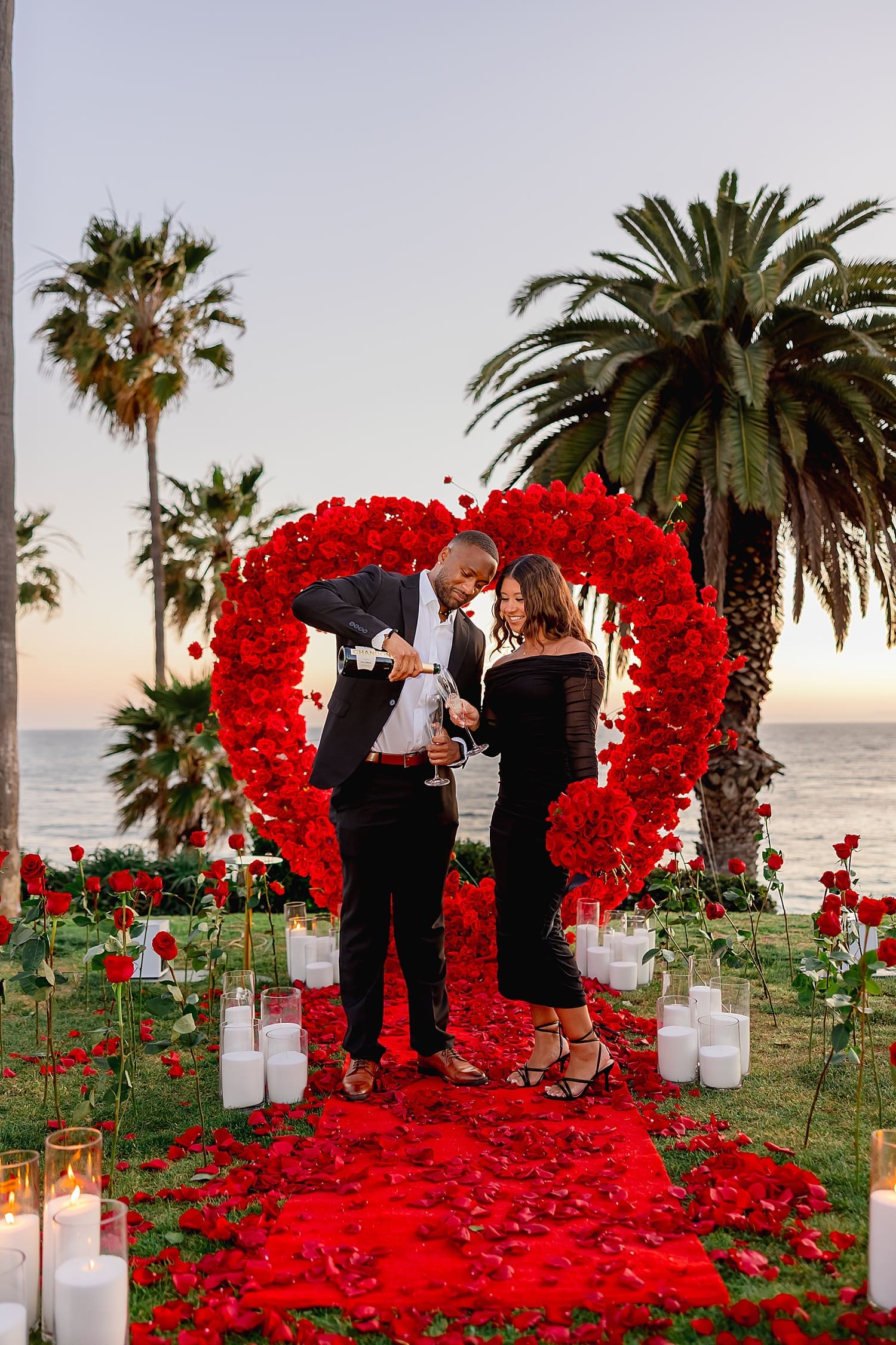 couple pours champagne to celebrate Coastal Sunset Proposal
