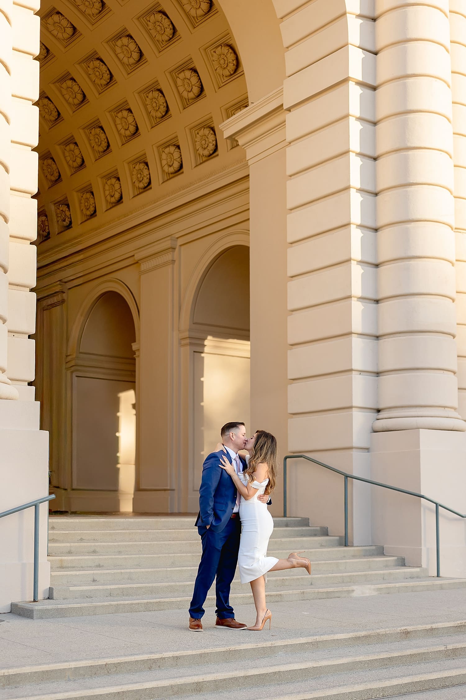 couple shares a little kiss on steps leading to courthouse by Southern California Wedding Photographer
