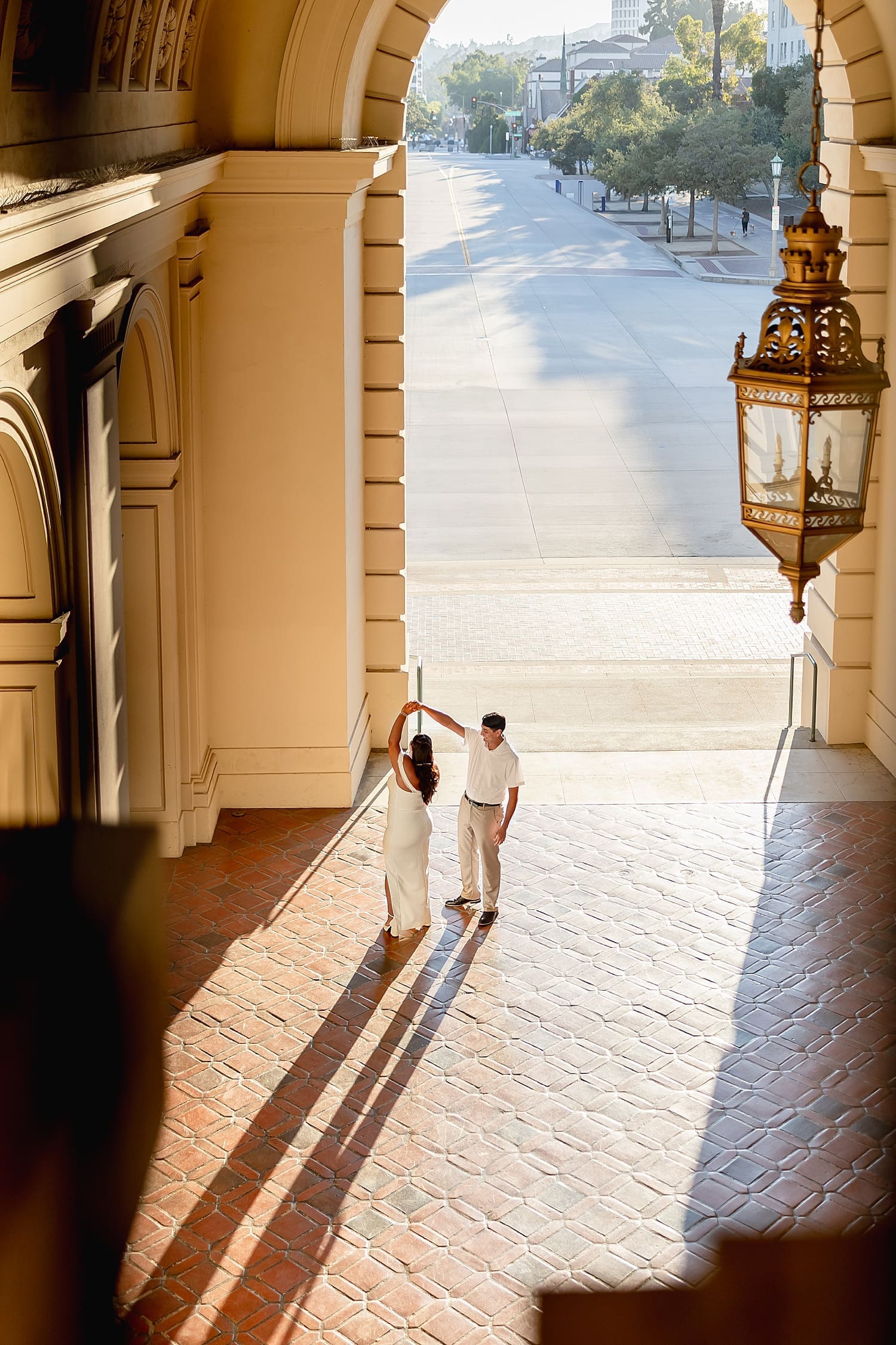 man twirls bride-to-be in open atrium under stone arch by Desiree Ashley Photography