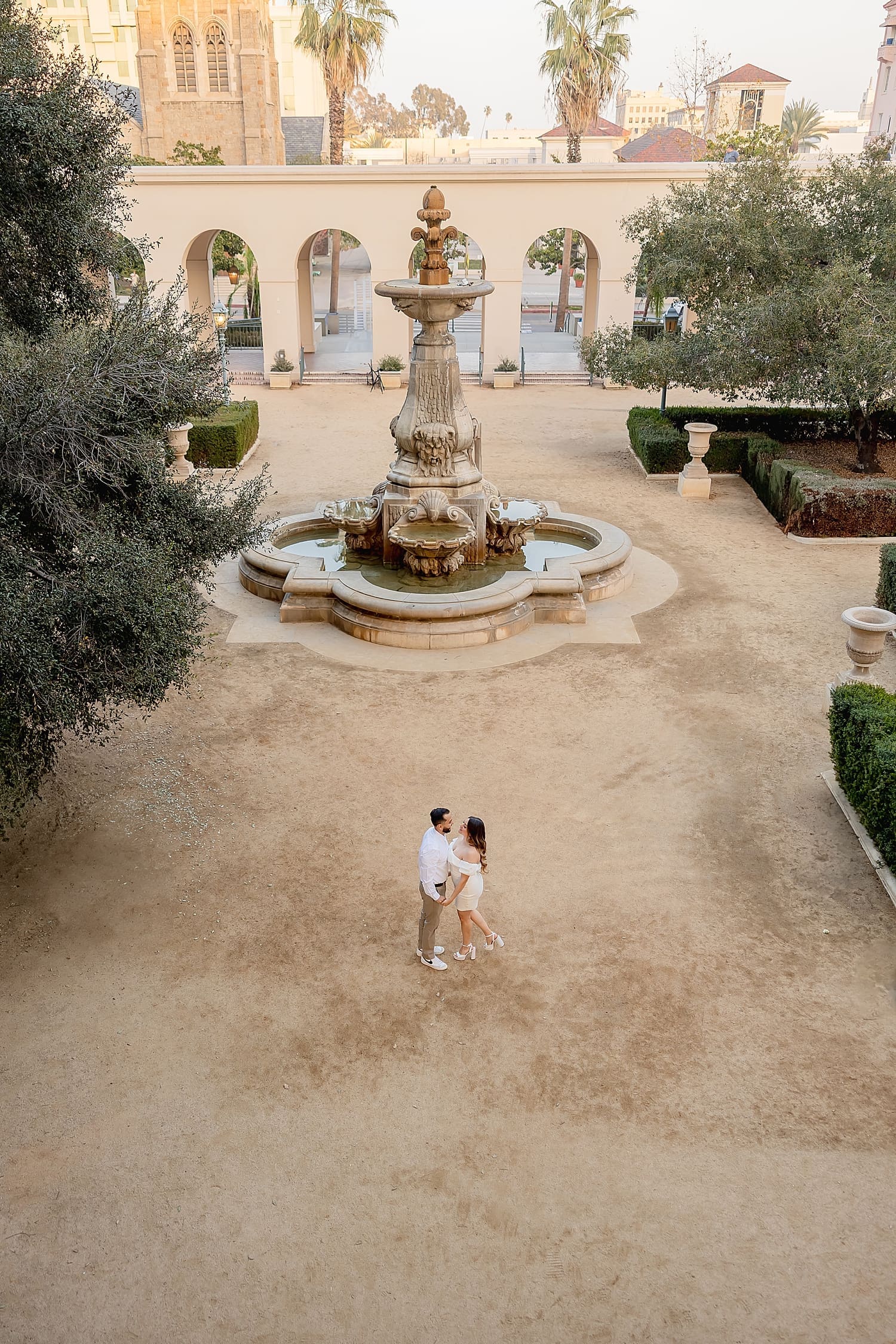 couple stands in big courtyard with fountain by Desiree Ashley Photography