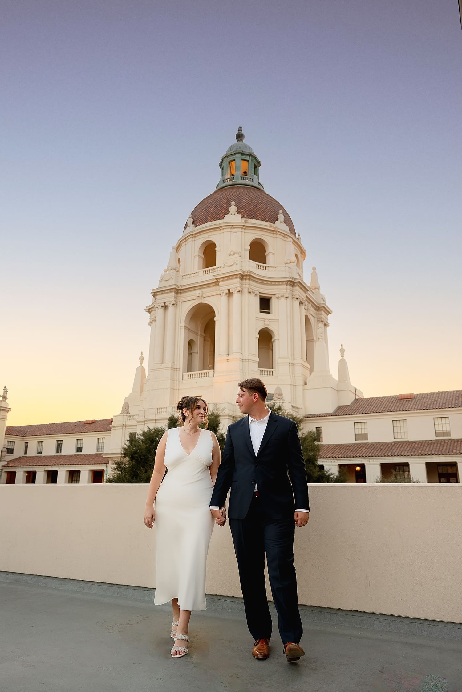 two people walk hand in hand on a rooftop at sunset by Desiree Ashley Photography