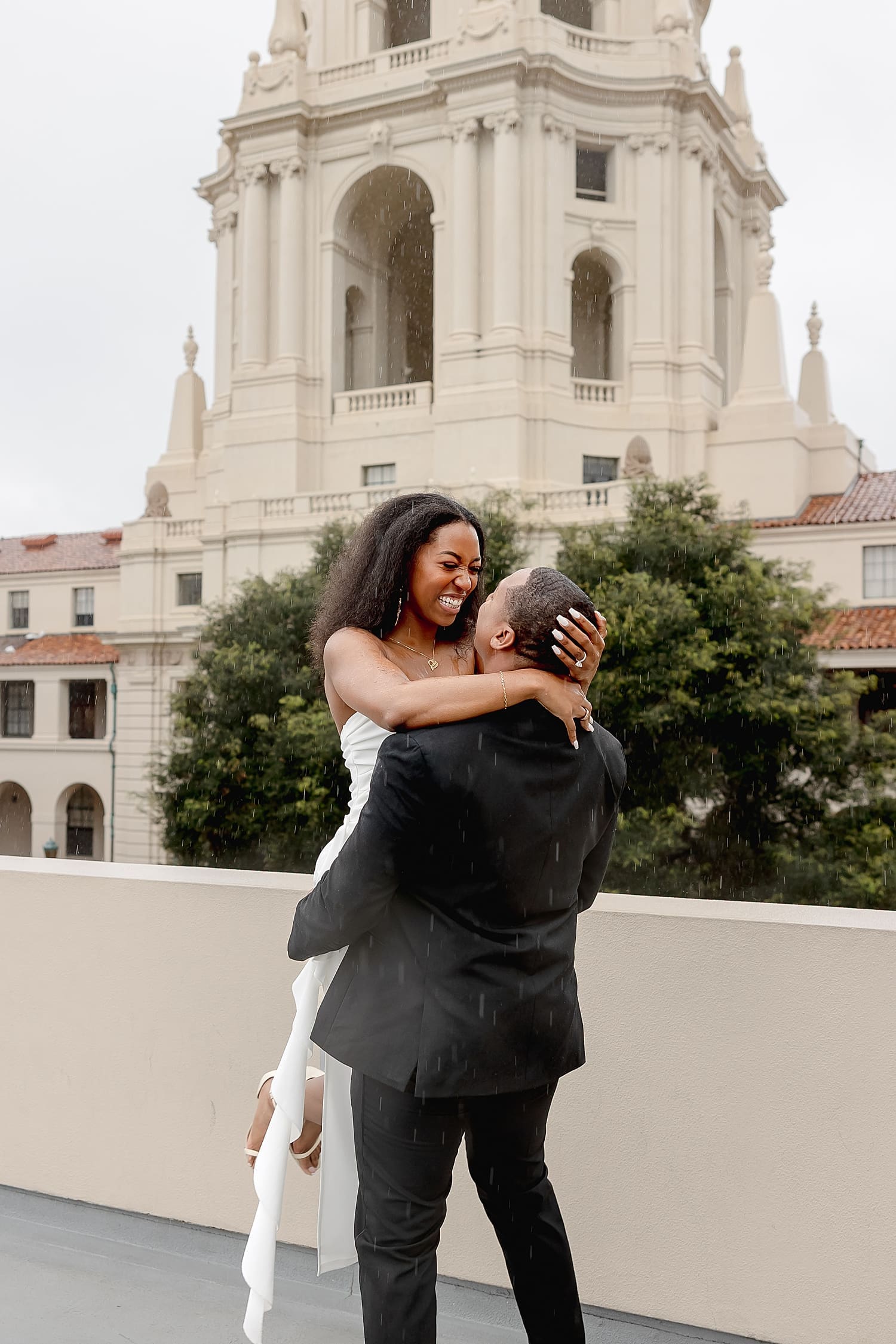 Man lifts up his bride for a twirl on the rooftop at Pasadena City Hall