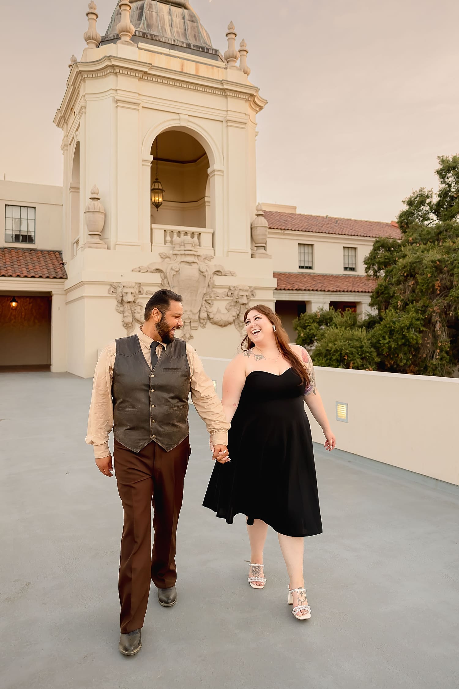 man and woman walk hand in hand in front of impressive venue by Southern California Wedding Photographer