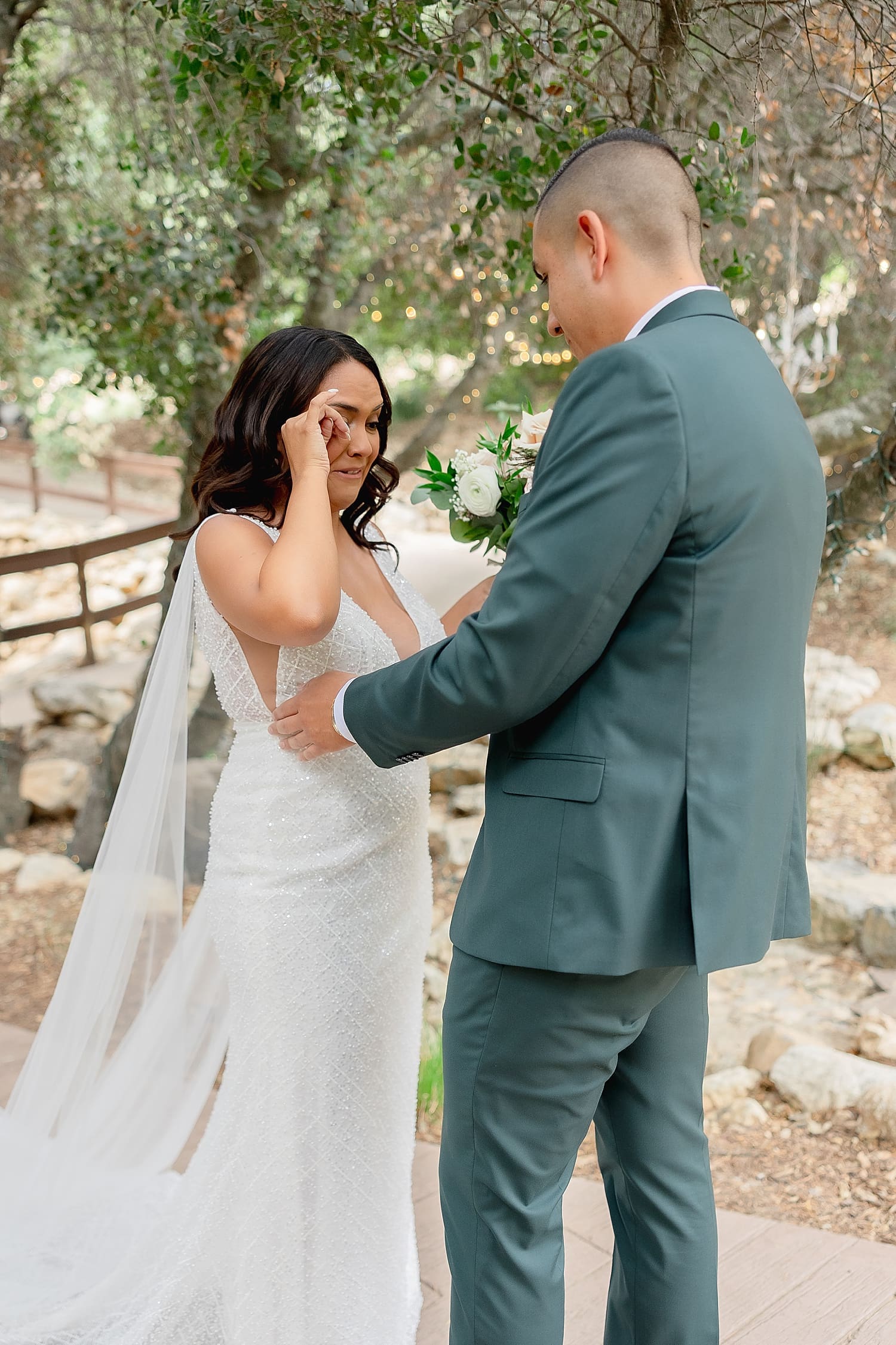 brunette wipes tears from her eyes during first look by Southern California wedding photographer