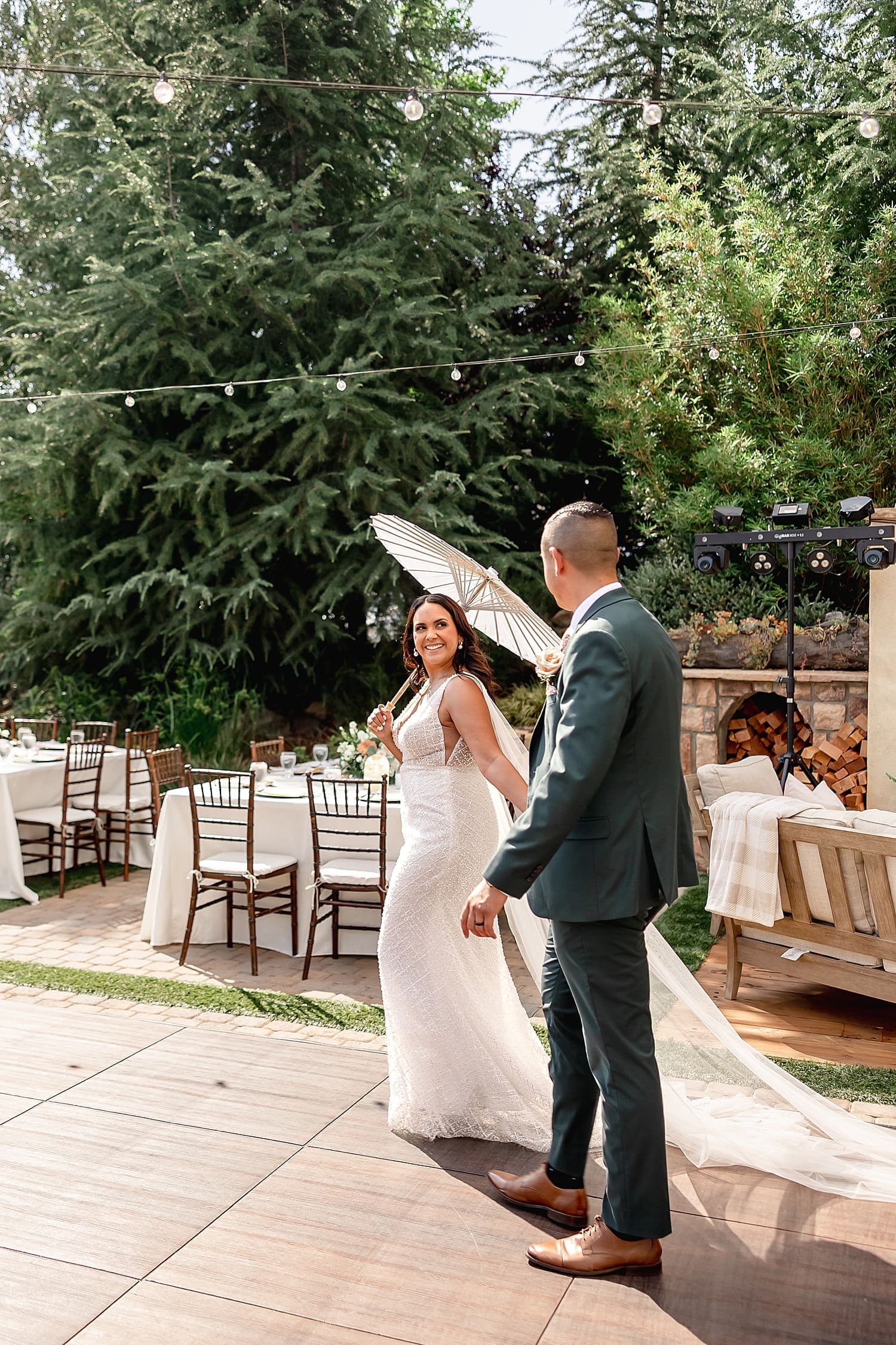 brunette woman in long white dress holds parasol walking with her man by Southern California wedding photographer