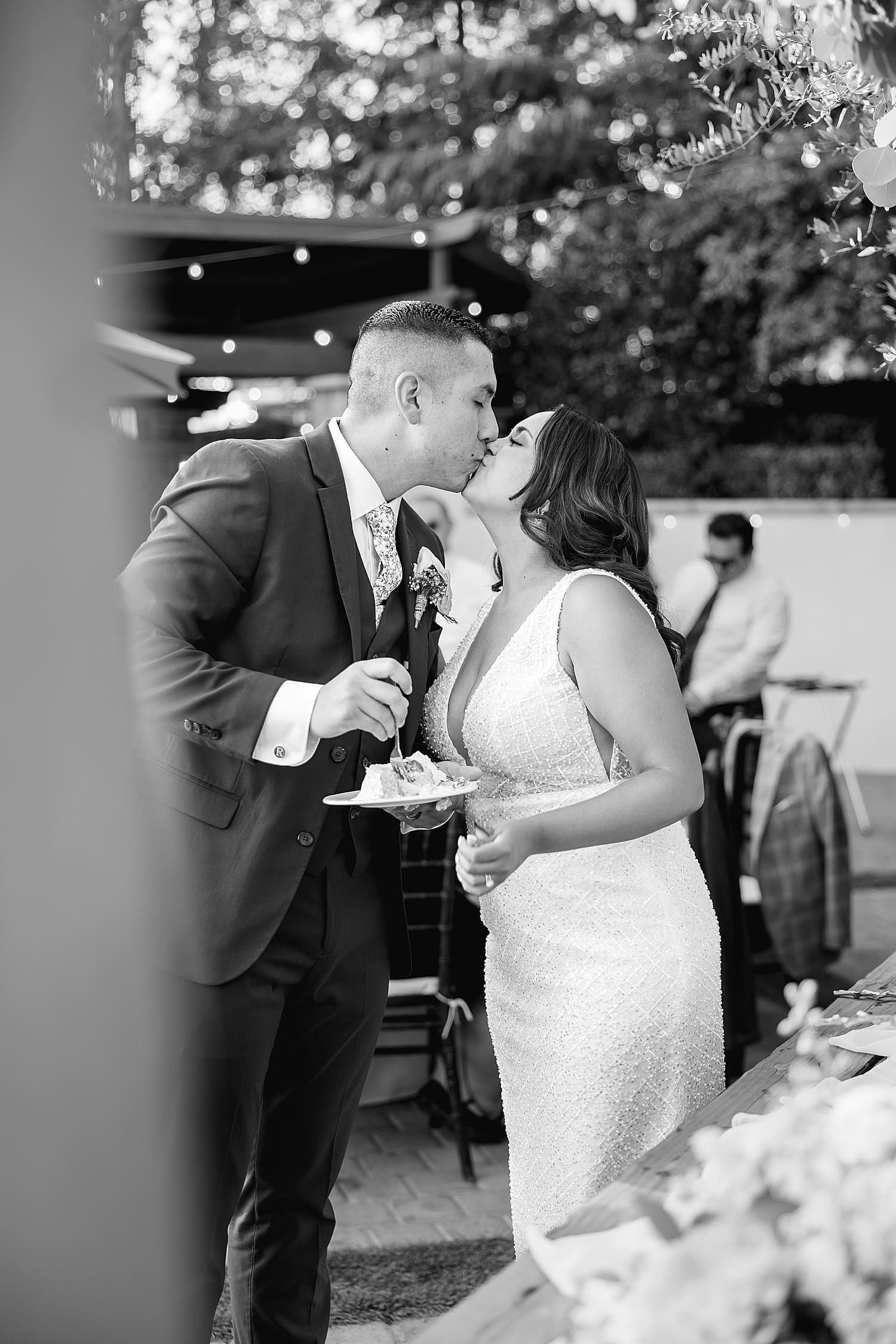 bride and groom share a kiss after cutting their cake by Southern California wedding photographer