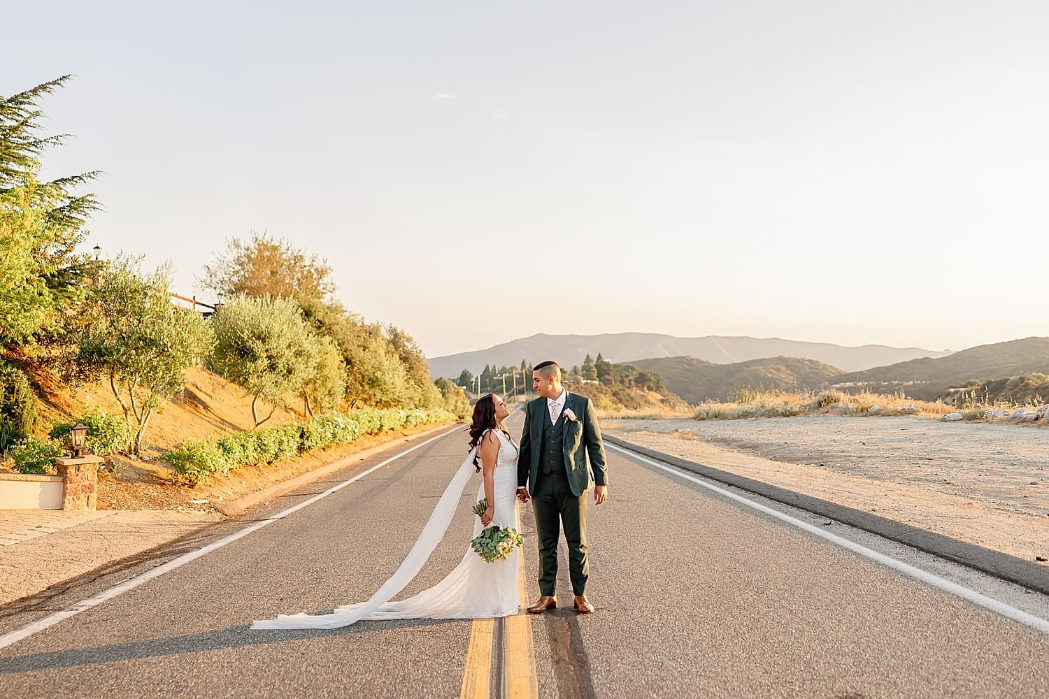 newlyweds cross road outside of at Serendipity Gardens during golden hour