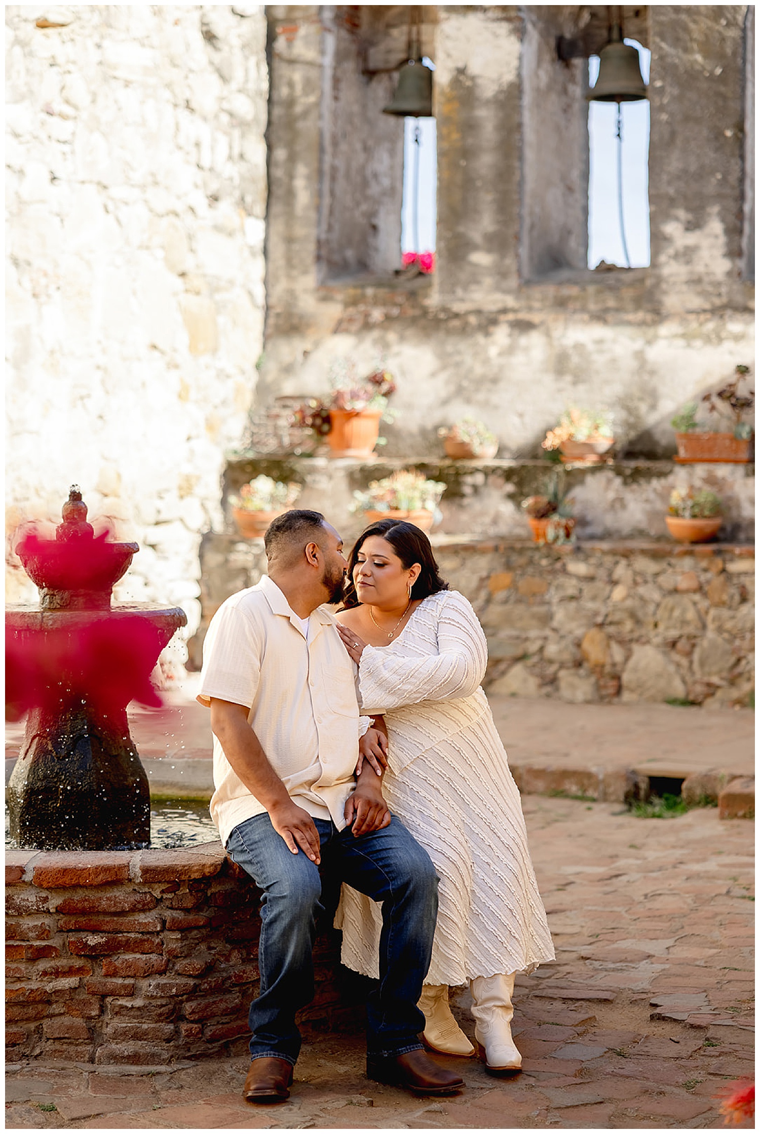 couple embrace while sitting on water fountain by Desiree Ashley Photography