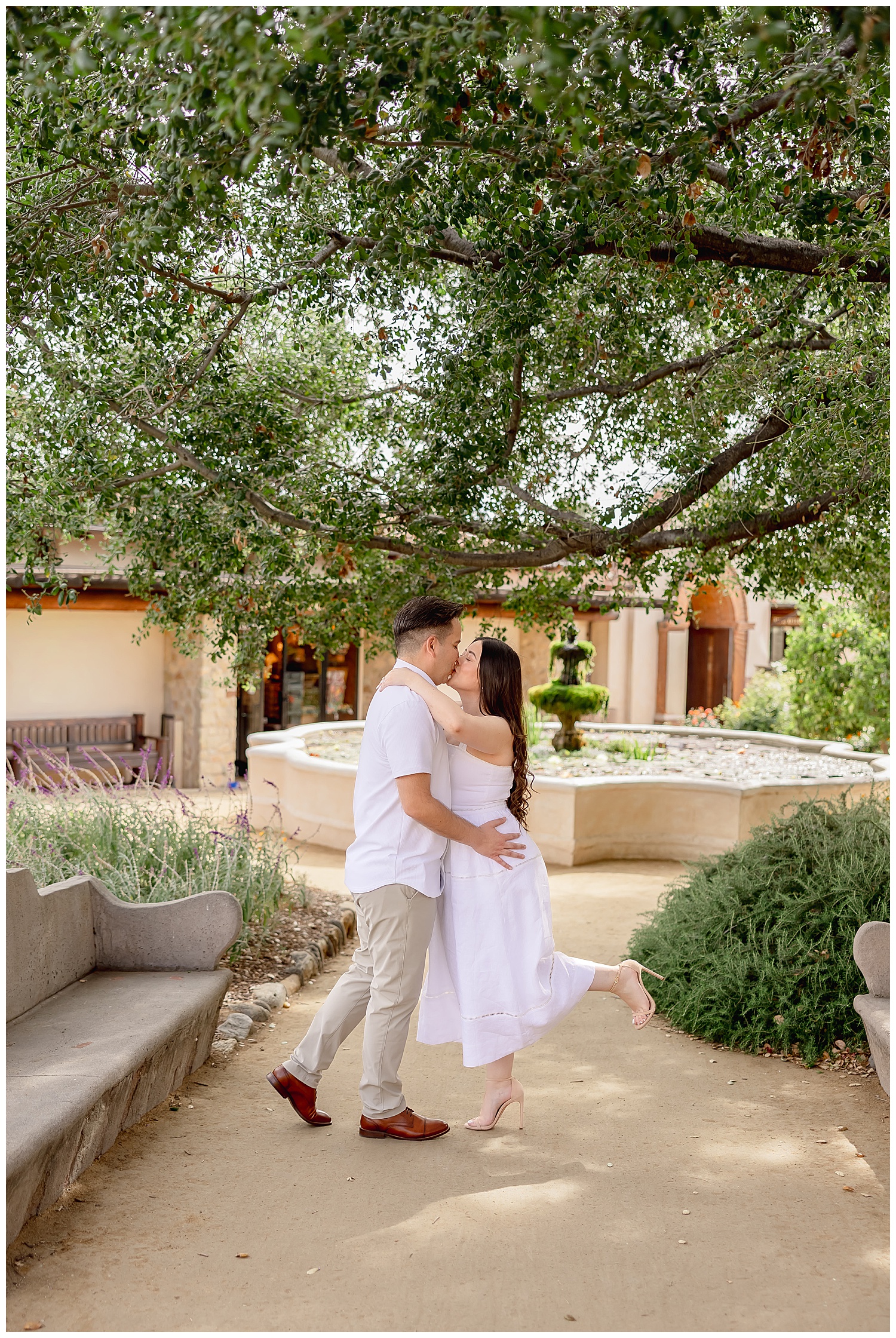 engaged couple kiss in front of water fountain by Desiree Ashley Photography