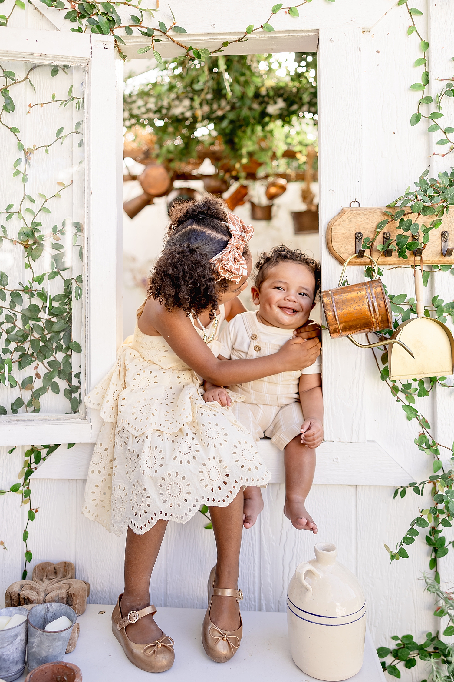 big sister holds baby brother in window seat by Desiree Ashley Photography