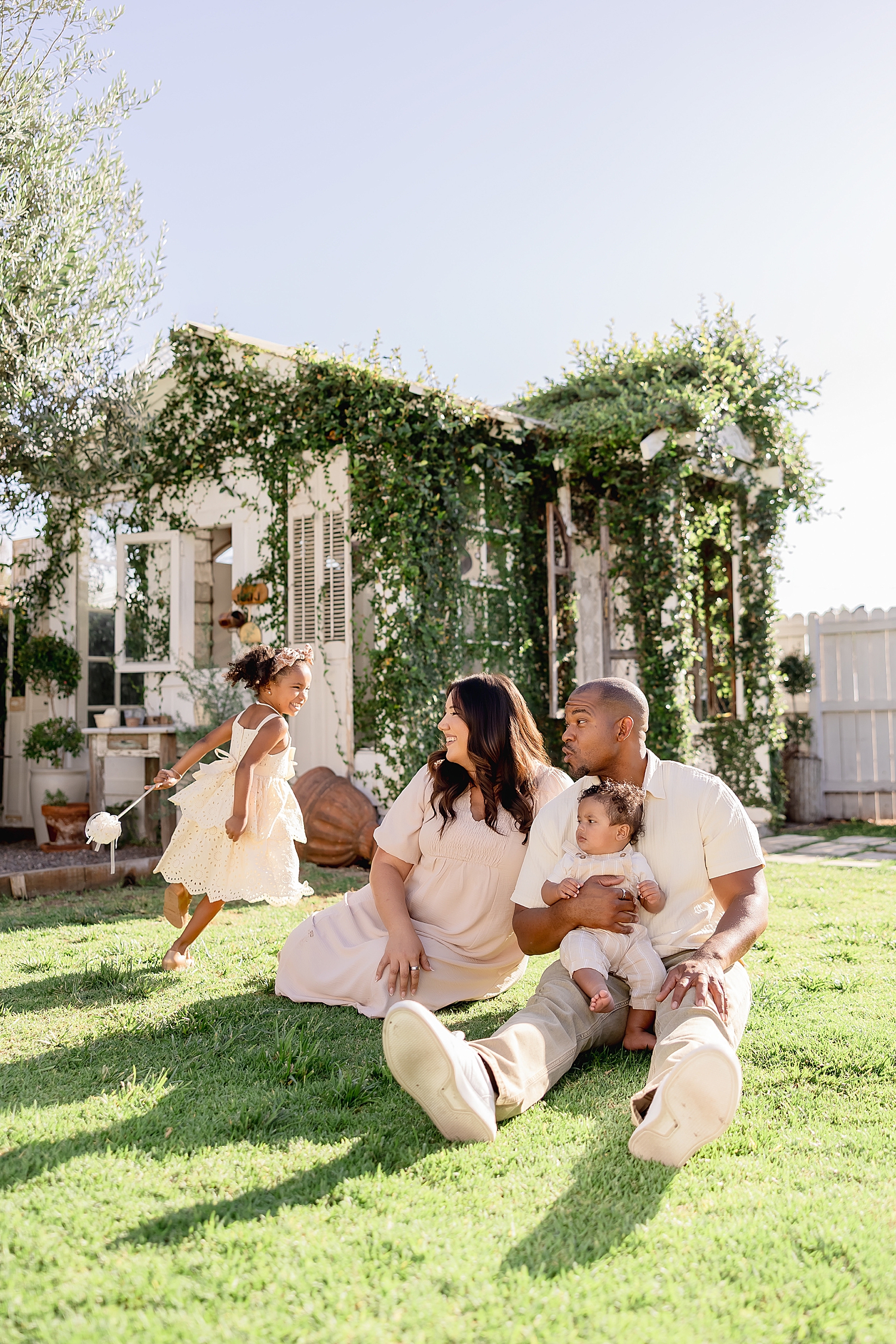 parents sit in the lawn while toddler runs around them by Desiree Ashley Photography